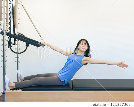 マシンピラティスのトレーニングをする女性 マシンピラティスのトレーニングをする女性 121837363