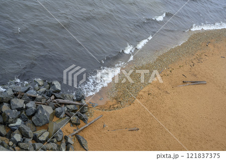 Top view of the sandy shore of Lake Baikal with rocks and wreckage of trees 121837375