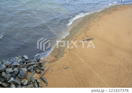 Top view of the sandy shore of Lake Baikal with rocks and wreckage of trees 121837376