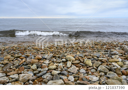 A wave on the pebbly shore of Lake Baikal under a misty sky 121837390