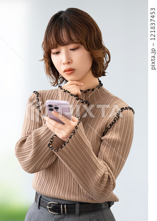 スマホを見て考える女性・ビジネスウーマン 121837453