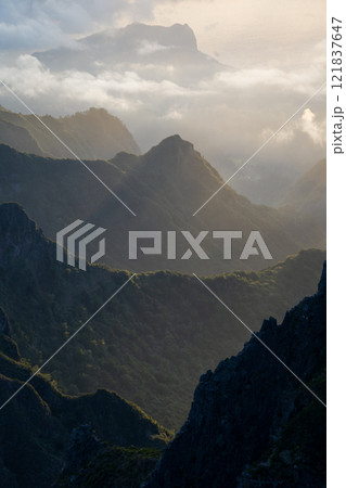Vertical foggy mountainous landscape catching first sunrays during sunrise, Madeira, Portugal 121837647