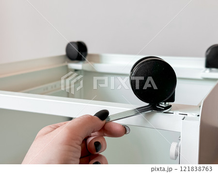 Hand adjusting caster wheels on white metal frame Hand adjusting caster wheels on white metal frame 121838763