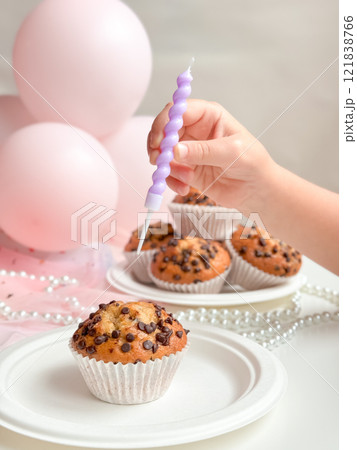 Child celebrating with chocolate chip muffins and pink balloons. Birthday concept 121838766