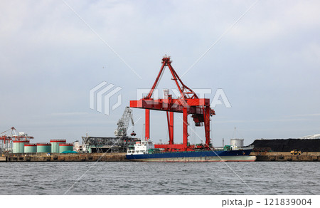 Large crane works on large coal stockpile and container crane at Industrial port for cargo container ship. Cargo transportation and activity at modern shipping container terminal. 121839004