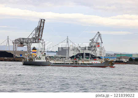 Container port at Osaka Japan, Large crane works on large coal stockpile at Osaka port. Cargo transportation and activity at modern shipping container terminal. Container port at Osaka Japan, Large crane works on large coal stockpile at Osaka port. Cargo transportation and activity at modern shipping container terminal. 121839022