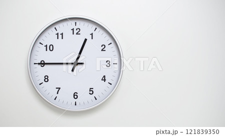 Minimalist White Clock with Silver Frame Striking 12.45/00.45 on White Background. Perfect for Time Management and Corporate Campaigns 121839350
