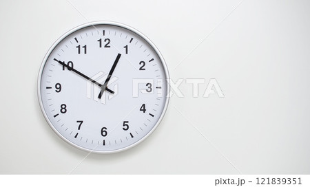 Minimalist White Clock with Silver Frame Striking 12.50/00.50 on White Background. Perfect for Time Management and Corporate Campaigns Minimalist White Clock with Silver Frame Striking 12.50/00.50 on White Background. Perfect for Time Management and Corporate Campaigns 121839351