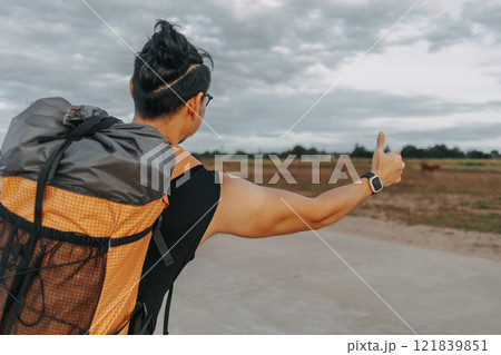 Man tourist backpacker hitchhike for pickup on the local country road. Man tourist backpacker hitchhike for pickup on the local country road. 121839851