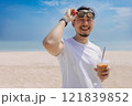 Happy man with hair bun style enjoy the iced coffee walking on the beach. 121839852