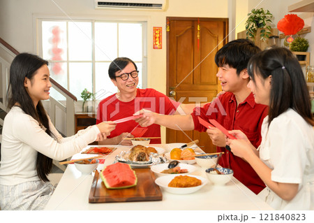 Cheerful Chinese family exchange traditional red envelopes or hongbao during a festive Chinese New Year celebration 121840823