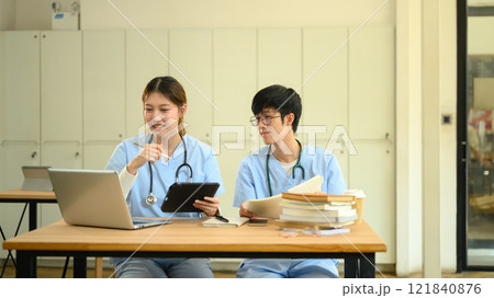 Medical students in scrubs discussing and analyzing information on laptop Medical students in scrubs discussing and analyzing information on laptop 121840876