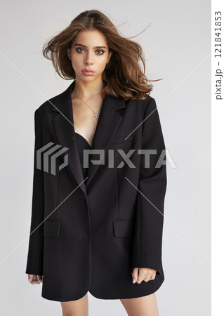 Beautiful European woman with dark hair In Oversized Black Blazer looks camera isolated on white background. Portrait Fashion model posing in studio, beauty, elegance and modern style 121841853