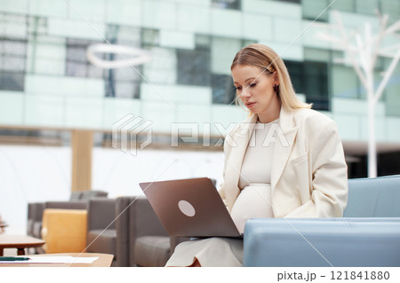 Beautiful pregnant business woman working indoors with a laptop. Pregnant female entrepreneur multitasking in office space, managing business tasks with professionalism and efficiency Beautiful pregnant business woman working indoors with a laptop. Pregnant female entrepreneur multitasking in office space, managing business tasks with professionalism and efficiency 121841880
