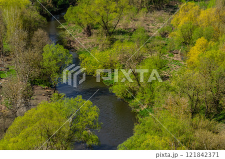 Lush green landscape with a winding river under clear blue sky in spring 121842371