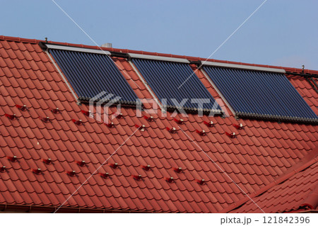 Solar panels on a red tiled roof harnessing renewable energy during daylight in a suburban area Solar panels on a red tiled roof harnessing renewable energy during daylight in a suburban area 121842396