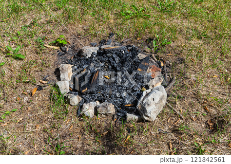 Fire pit remnants after a summer gathering in a grassy outdoor area 121842561
