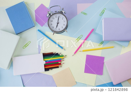 Back to school concept. Alarm clock, notebooks, pencils, paper clips and textbooks on colorful background, pastel colors. Back to school concept. Alarm clock, notebooks, pencils, paper clips and textbooks on colorful background, pastel colors. 121842898