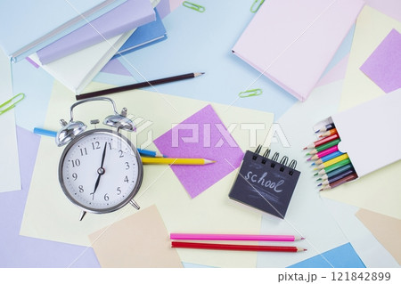 Back to school concept. Alarm clock, notebooks, pencils, paper clips and textbooks on colorful background, pastel colors. 121842899