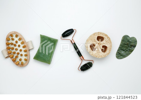 Eco-friendly beauty essentials, including soap, loofah sponge, marble face roller, embodying a sustainable self-care concept 121844523