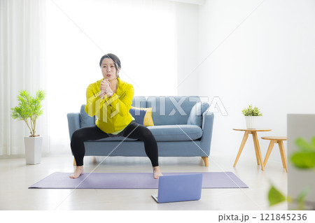 リビングでエクササイズをする若い女性 リビングでエクササイズをする若い女性 121845236