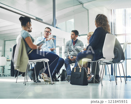 Group of talking business professionals sitting together in a circle for a team meeting. A bunch of design employees and senior leader working, having a strategy and planning session in modern office Group of talking business professionals sitting together in a circle for a team meeting. A bunch of design employees and senior leader working, having a strategy and planning session in modern office 121845931