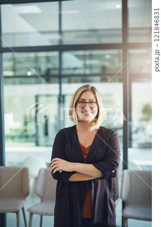 Proud, arms crossed and confident businesswoman standing alone in a modern office. Young female business owner smiling in a corporate workplace. Happy and successful lady at work with copy space. Proud, arms crossed and confident businesswoman standing alone in a modern office. Young female business owner smiling in a corporate workplace. Happy and successful lady at work with copy space. 121846831