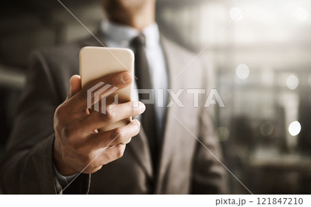 Businessman browsing on his phone online to look at his social media in the office, close up. Corporate professional in a suit reading a sms message. Male executive checking his news feed 121847210