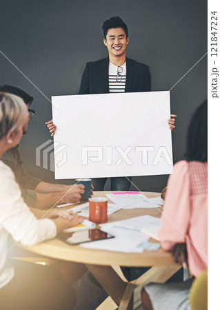 Casual, creative team doing a fun presentation with a blank card, billboard or poster in a modern office. Happy diverse team working together, sharing an idea or business plan while brainstorming 121847224