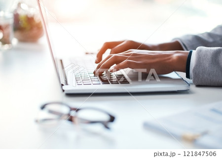 Businesswoman typing work on a laptop at her desk in a modern office. Busy female doing business on keyboard working with reports, documents and emails or browsing the internet at the workplace. 121847506