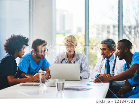 Team of doctors in a meeting planning and brainstorming in a boardroom using a laptop to read notes. Group of healthcare professionals discussing and talking in a modern office 121847521