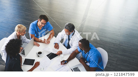 Doctor, nurse and healthcare professional team or group sitting in the boardroom, talking about medicine and discussing treatment during a meeting. Planning and brainstorming a health cure from above 121847599