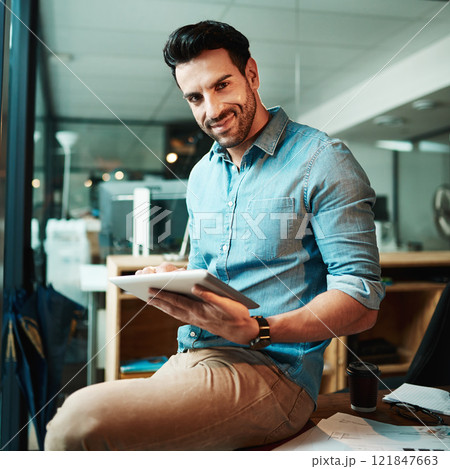 Confident businessman with tablet holding, browsing and searching online while working overtime on startup company. Portrait of smiling, happy and successful creative finishing deadline on technology 121847663