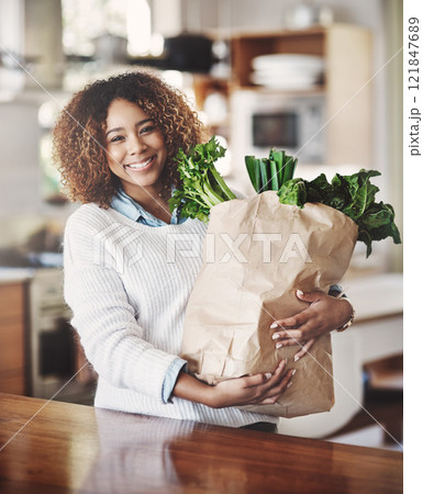Healthy, fresh and organic vegetables in a shopping bag at home with a happy black woman in a kitchen. Portrait of smiling African American female excited about starting diet or weight loss journey 121847689