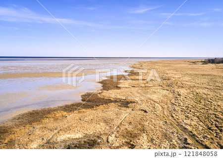 Copy space, blue sky and beach sand on a sea or ocean shore on a private, secluded and quiet island. Landscape view of a calm, serene and peaceful lake or bay with copyspace to relax and enjoy summer 121848058
