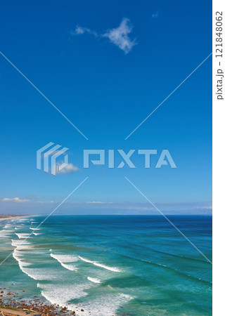 Beautiful and relaxing view of ocean, beach and a cloudy blue sky with copy space background. Landscape of calm and remote sea with waves rolling onto the shore in natural environment on a sunny day 121848062