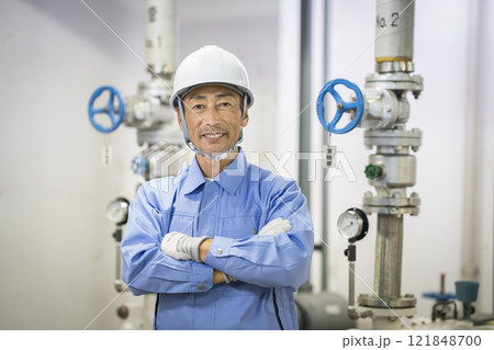 カメラ目線で腕組みをした作業服姿のシニア男性　ビルメンテナンススタッフ　イメージ　 121848700
