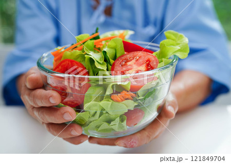 Asian elderly woman patient eating pork chop stake and vegetable salad for healthy food in hospital. 121849704