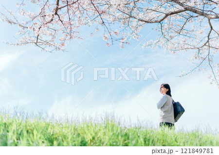 桜の咲いた河川敷を通学する女子高生 121849781