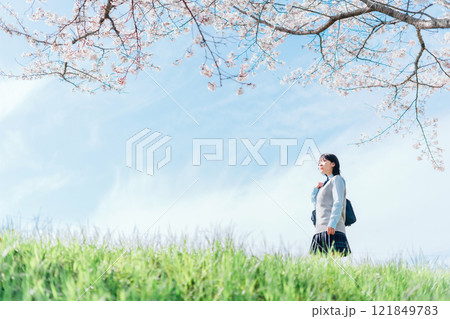 桜の咲いた河川敷を通学する女子高生 121849783