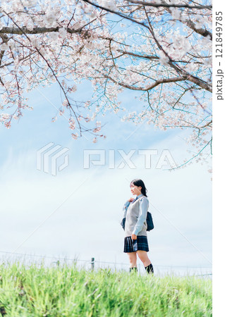 桜の咲いた河川敷を通学する女子高生 121849785