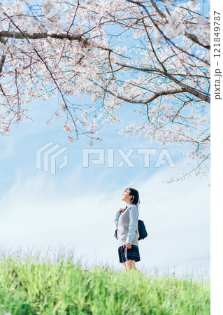 桜の咲いた河川敷を通学する女子高生 桜の咲いた河川敷を通学する女子高生 121849787