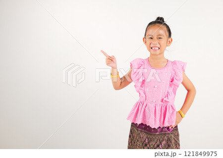 Portrait Thailand kid girl smiling traditional Thai dress costume indicate finger empty space, studio isolated white background, kindergarten child pointing index out with copy space 121849975