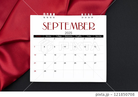 September 2025 Monthly desk calendar with red silk on black leather background. 121850708