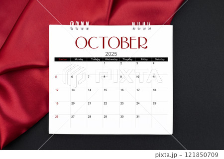 October 2025 Monthly desk calendar with red silk on black leather background. 121850709