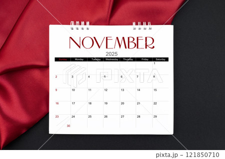 November 2025 Monthly desk calendar with red silk on black leather background. 121850710