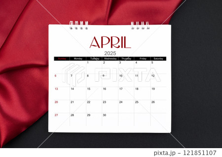 April 2025 Monthly desk calendar with red silk on black leather background. 121851107
