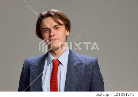 portrait of young confident man standing, looking at camera with warm smile, dressed formalwear, against grey studio background. portrait of young confident man standing, looking at camera with warm smile, dressed formalwear, against grey studio background. 121851273