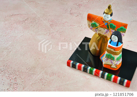 ピンク背景のひな人形（向かって左が男雛、右に女雛）コピースペース有り 121851706