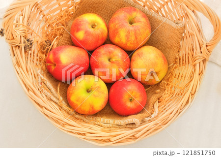 Apples in a straw basket. Orange ripe fruits. Apples consist of a large number of vitamins and nutrients. Top view. Apples in a straw basket. Orange ripe fruits. Apples consist of a large number of vitamins and nutrients. Top view. 121851750